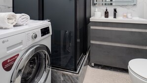 A modern bathroom with a washing machine, a toilet, and a sink. - Comfort 1-room apartments  (Almaty)