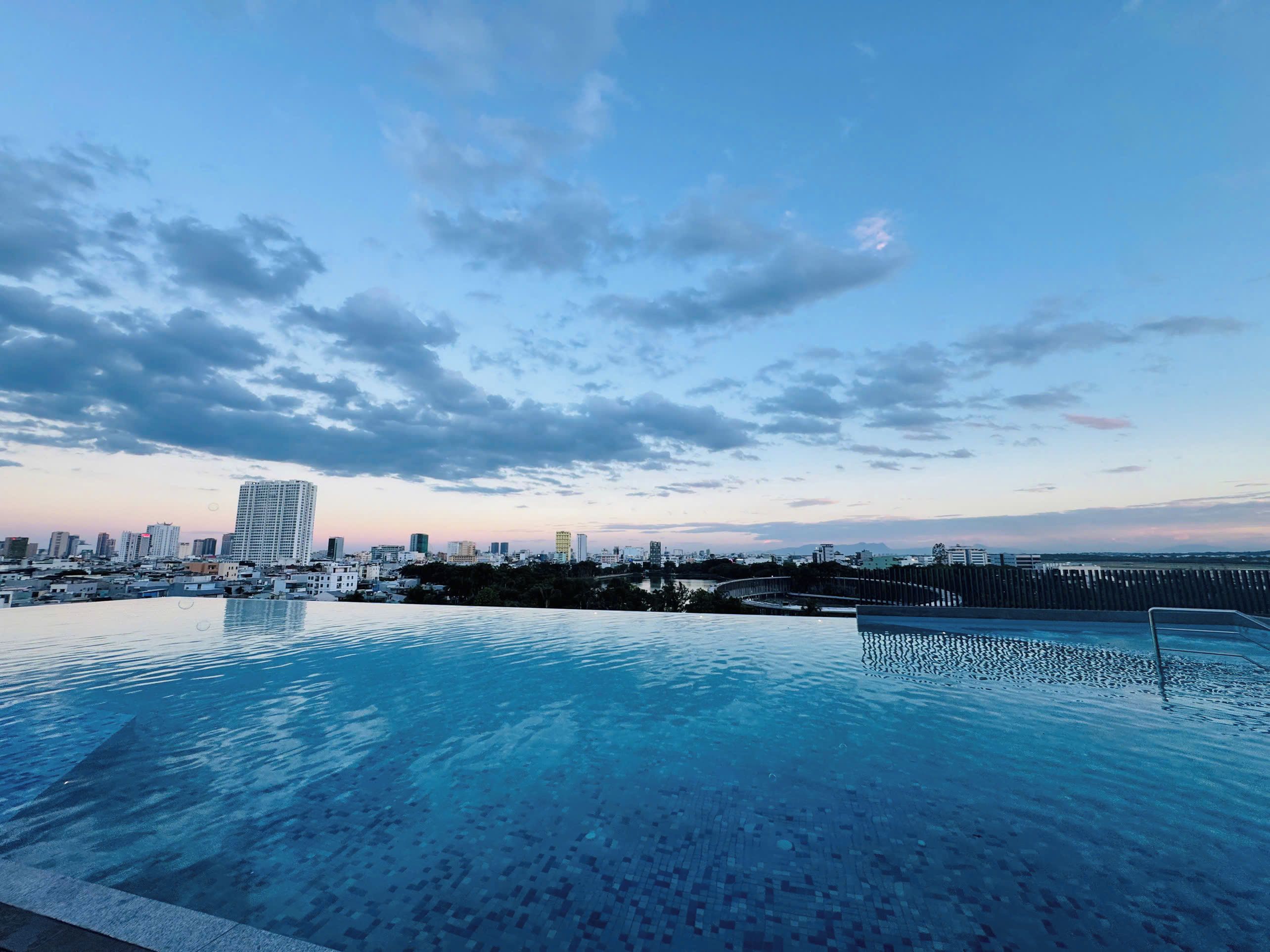 Una piscina infinita con un horizonte urbano de fondo.