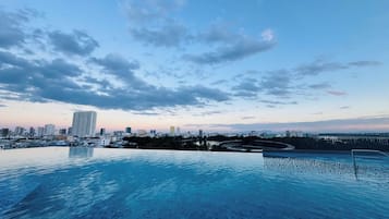 Una piscina infinita con un horizonte urbano de fondo.