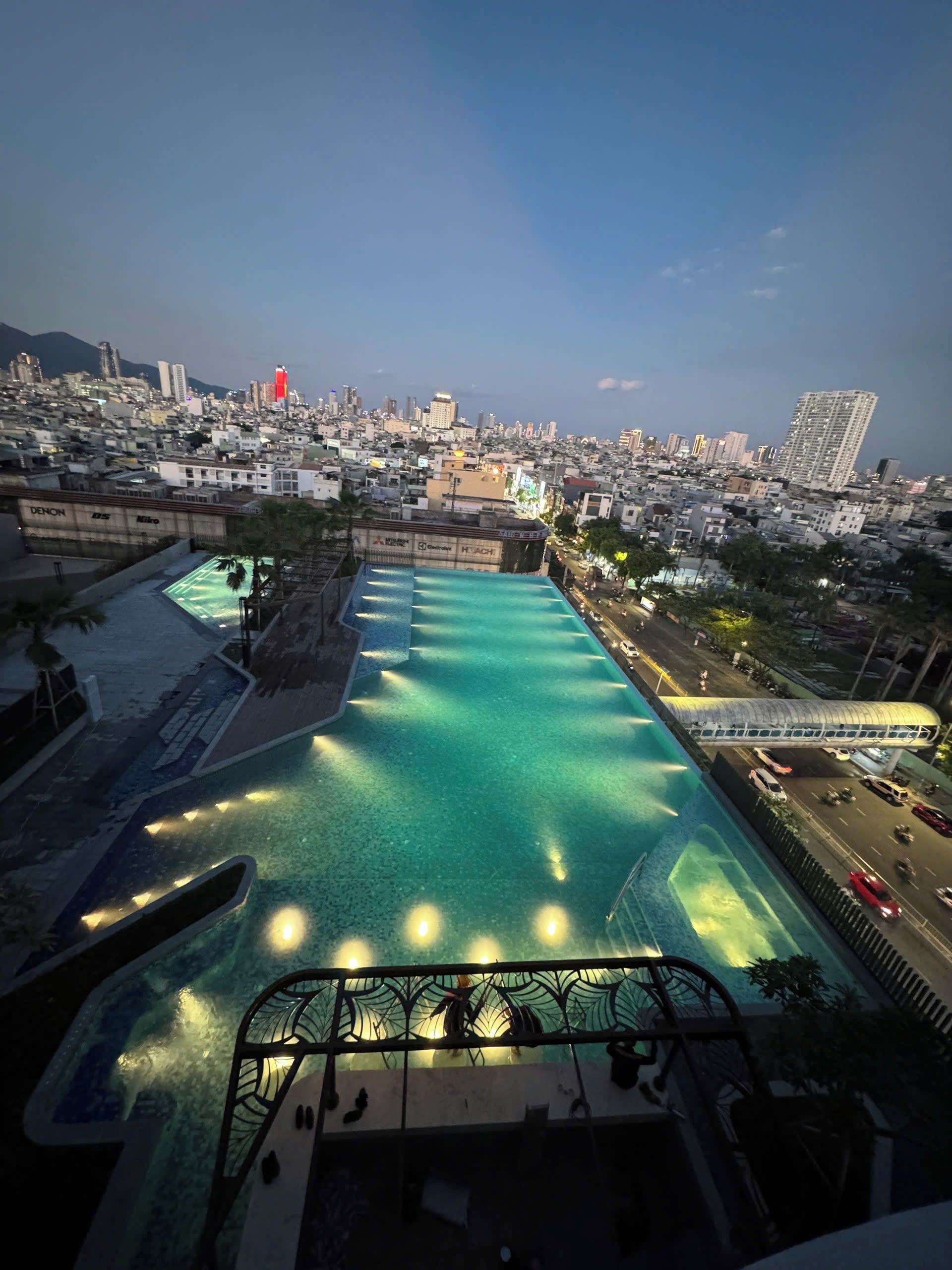 Una piscina en la azotea con vistas a un paisaje urbano al atardecer.