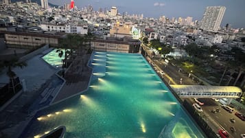 Una piscina en la azotea con vistas a un paisaje urbano al atardecer.