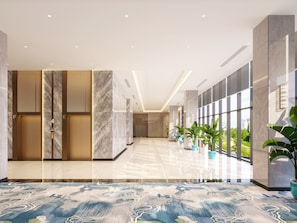 A modern lobby with marble flooring, a central elevator, and large windows offering a view of greenery.