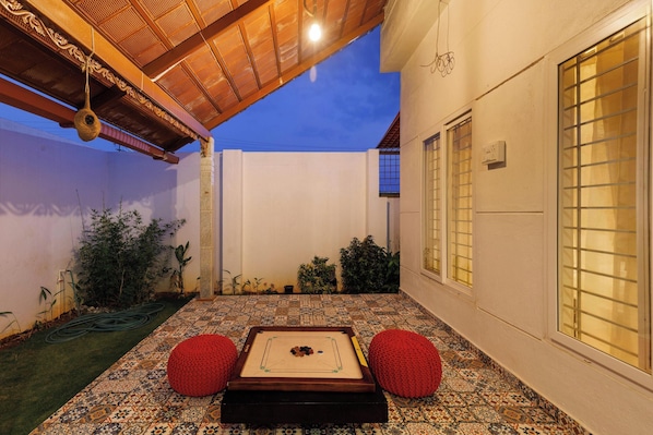 A courtyard with a pool table, red cushions, and a pergola.