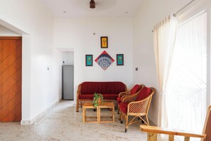 A living room with a sofa, chairs, a table, and a potted plant. - Dew Drop Villa by Stayjade 3bhkpvt Pool Garden (Bengaluru)