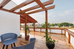 A covered outdoor balcony with a wooden pergola, two blue chairs, and potted plants. - Dew Drop Villa by Stayjade 3bhkpvt Pool Garden (Bengaluru)