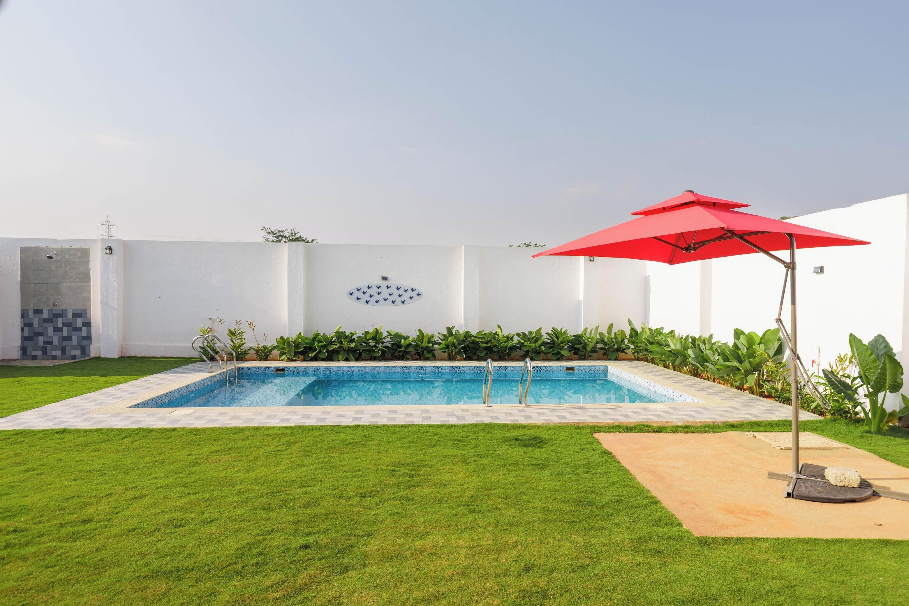 A rectangular swimming pool with a tiled edge, surrounded by a well-maintained lawn.