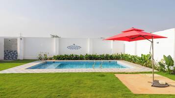 A rectangular swimming pool with a tiled edge, surrounded by a well-maintained lawn.