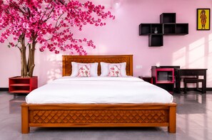Ein Schlafzimmer mit einem hölzernen Bett, einem roten Nachttisch, einer schwarzen TV-Konsole und einem großen, blühenden Rosendorn.