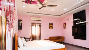 A bedroom with a bed, a wooden chair, a television, an air conditioning unit, and a ceiling fan. - Cherryblossom by Redolive3bhkecr Beachesit Park (Tirupporur)