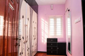 A room with a wardrobe, a dresser, a window, and a mirror.