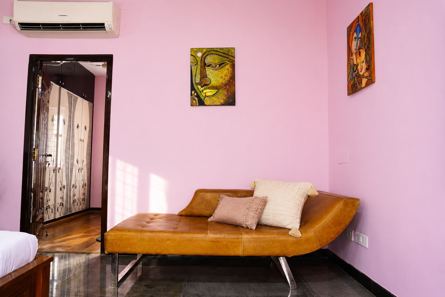 A room with a brown sofa, a bed, and a door with decorative panels.