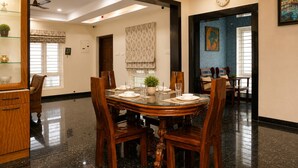 A dining area with a round table, chairs, and a clock on the wall. - Cherryblossom by Redolive3bhkecr Beachesit Park (Tirupporur)