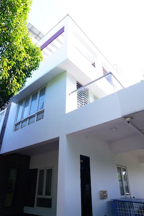 A modern two-story building with large windows, a flat roof, and a visible balcony.