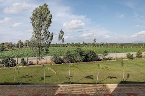 A view of a landscaped area with a grassy field, trees, and a distant mountain range.