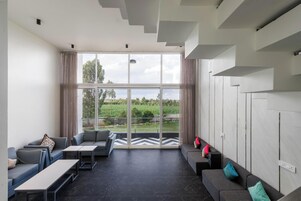 Una sala de estar moderna con un ventanal grande, un conjunto de sofá, una mesa de centro y una escalera.