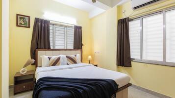 A bedroom with a bed, nightstand, lamp, and window with curtains.