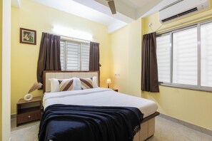 A bedroom with a bed, nightstand, lamp, and window with curtains. - City Haven by Jadecaps 3bhk South Kolkata (Kolkata)