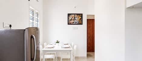 Una cocina moderna con un refrigerador de acero inoxidable, una mesa de comedor blanca con sillas y un ventilador de techo.