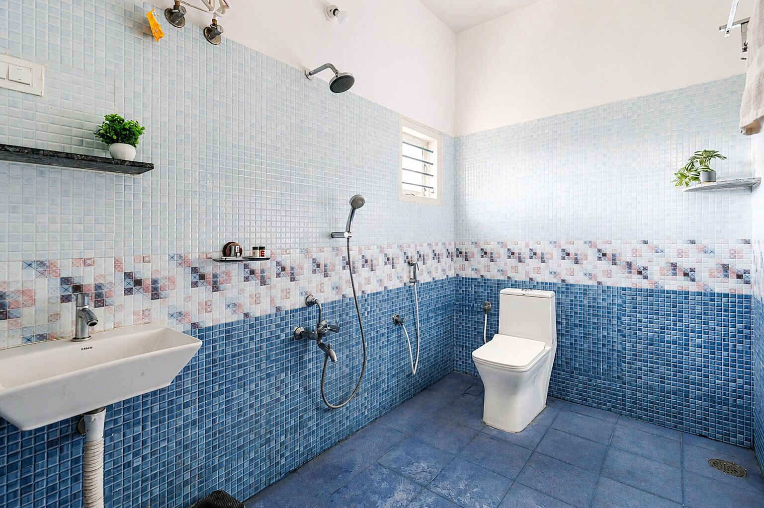 Un baño con lavamanos blanco, inodoro y ducha con cabezal de ducha manual.