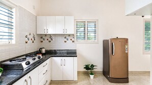 Uma cozinha com armários brancos, bancada preta, fogão de aço inoxidável e geladeira marrom.