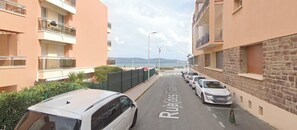 Eine Straße mit parkenden Autos und einem Gebäude mit Balkonen.