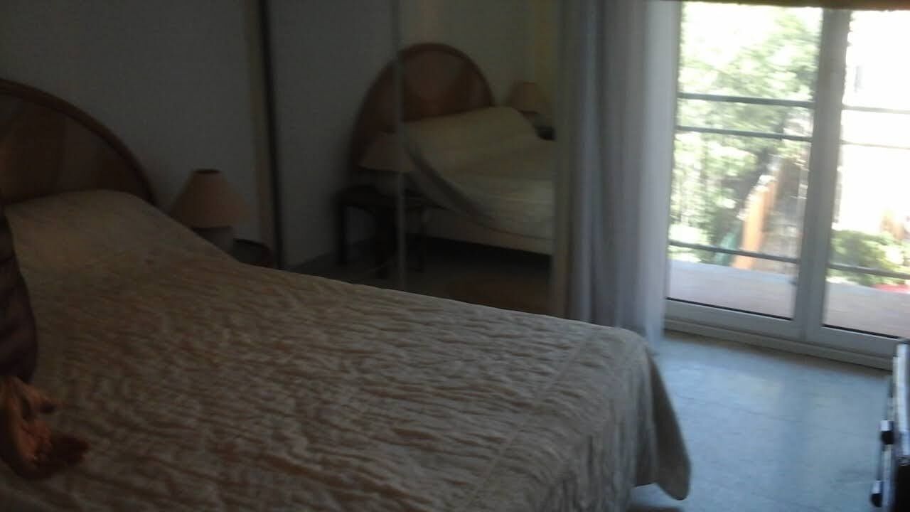 A bedroom with a bed, a chair, and a window.