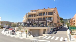A multi-story building with a ground-floor restaurant and upper-floor balconies. - Exceptional location, 30 meters from the beach, right in the center, with air conditioning (Cavalaire-sur-Mer)