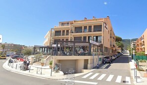 Ein mehrgeschossiges Gebäude mit einem Restaurant im Erdgeschoss und Balkonen in den oberen Stockwerken.