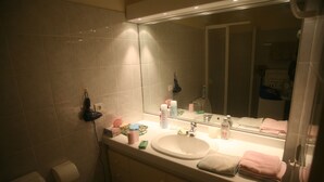 A bathroom with a sink, mirror, and toiletries. - Exceptional location, 30 meters from the beach, right in the center, with air conditioning (Cavalaire-sur-Mer)