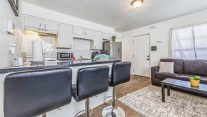 A compact living space with a kitchenette, a dining area with bar stools, and a seating area with a sofa and coffee table. - Coffield - Comfort, Privacy, and Convenience in Killeen, Texas (Killeen)