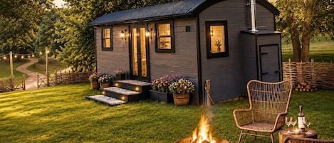 A small cabin with a fire pit and outdoor seating.