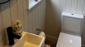 Ein Badezimmer mit Toilette, Waschbecken, einem Fenster mit Dekoration und einem Toilettenpapierhalter.