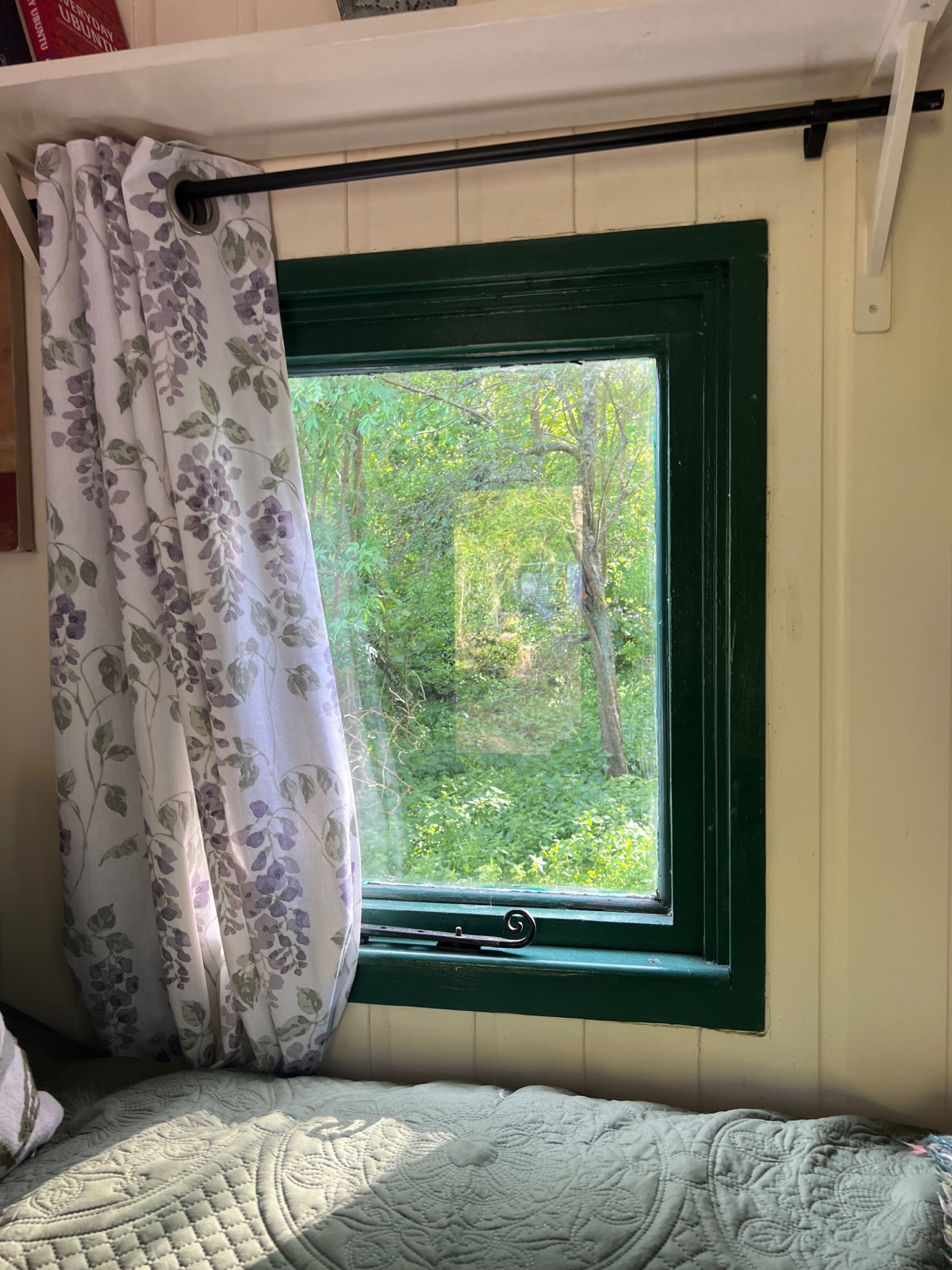 Ein Schlafzimmer mit Fenster, Bett und Vorhang.
