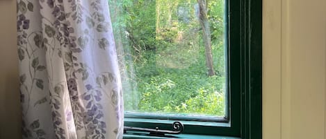 Ein Schlafzimmer mit Fenster, Bett und Vorhang.