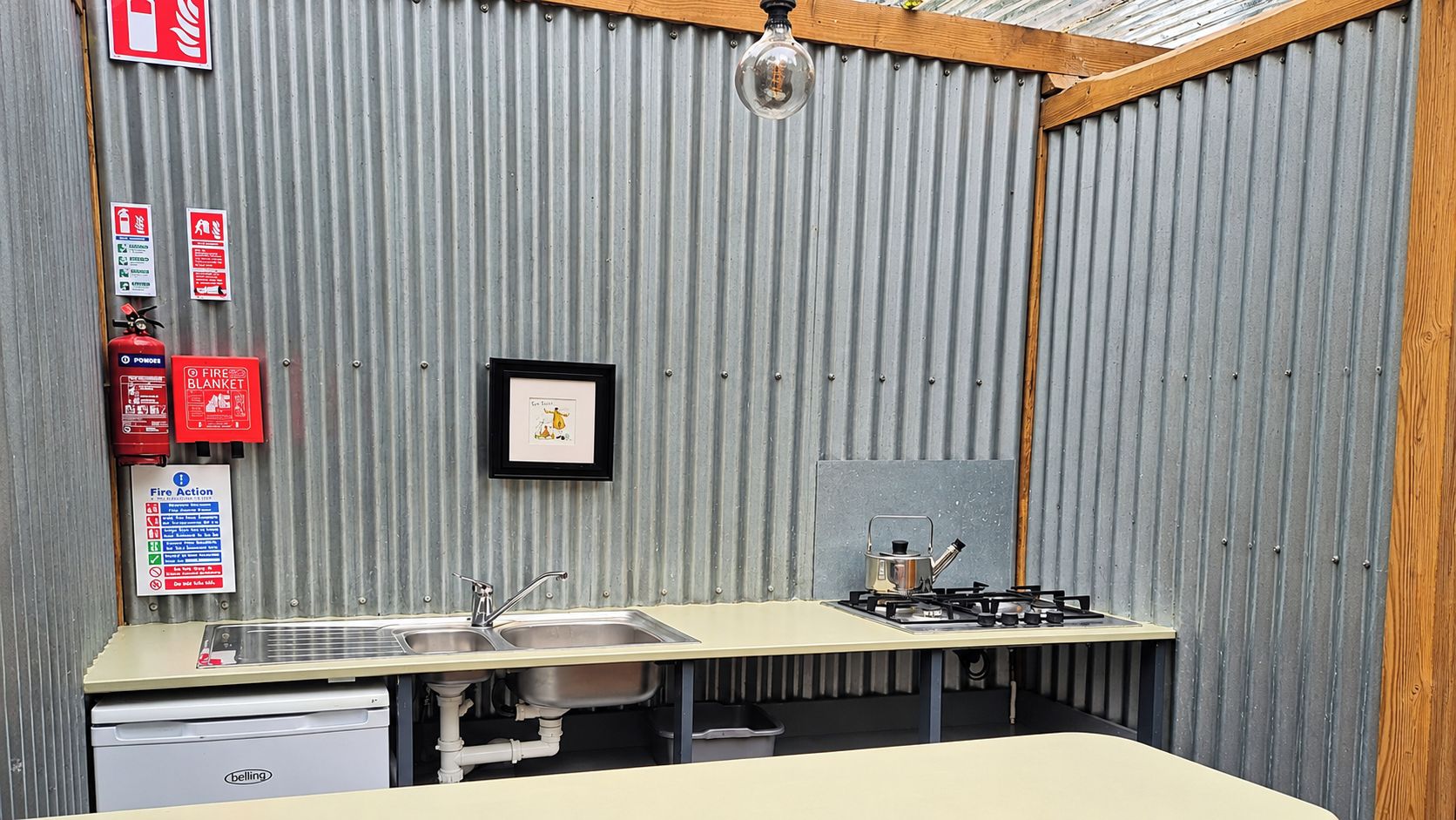 A compact kitchen with a sink, stove, and fire extinguisher.