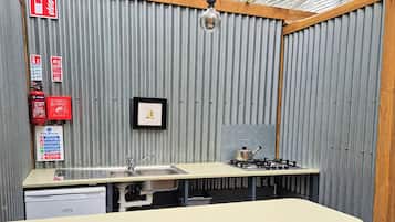 A compact kitchen with a sink, stove, and fire extinguisher.