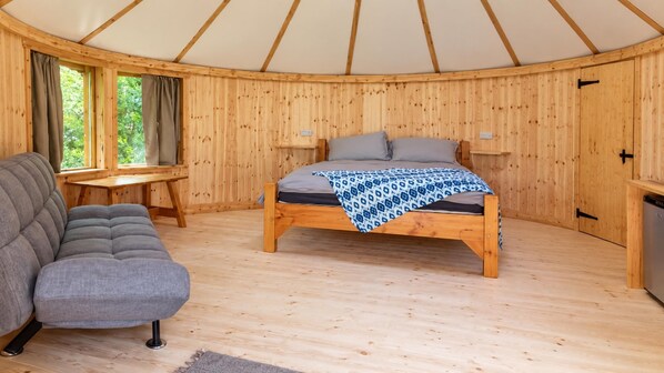 A room with a bed, a sofa, a table, and a window.