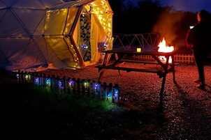 Una carpa con una mesa y un fuego, rodeada de botellas.