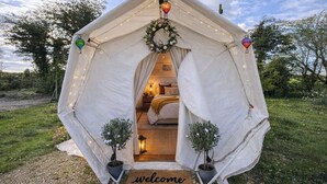 A tent with a 'welcome' mat, a bed, and two potted plants. - Pewsey Countryside Dome - Dog Friendly - Fire pit (Pewsey)