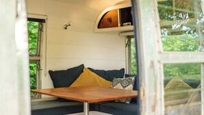 Un interior acogedor con un sofá, cojines, una mesa y un ventanal.