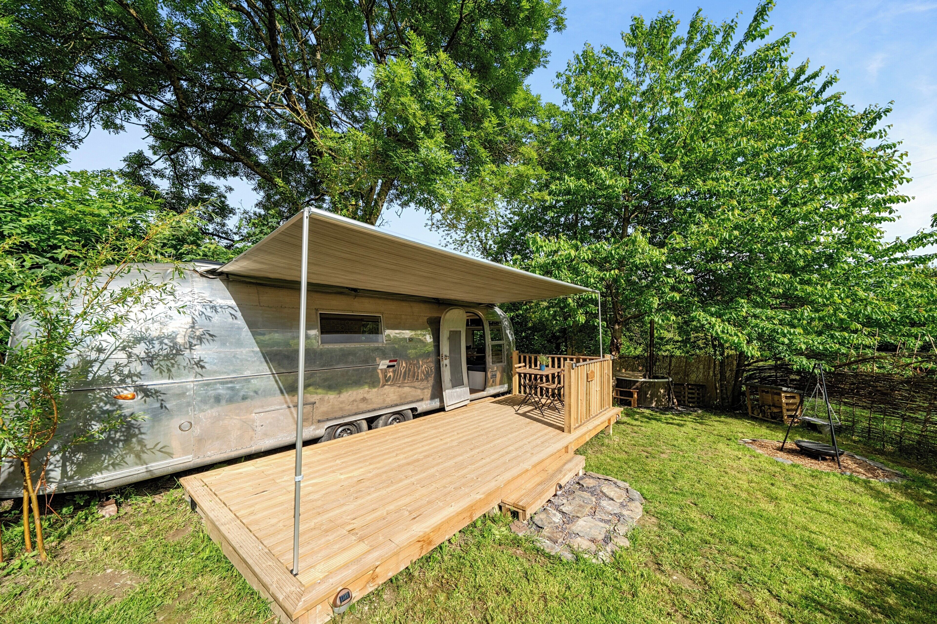 Un véhicule récréatif doté d’une terrasse en bois et d’un espace abrité.
