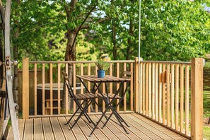 Um deck de madeira com uma mesa e cadeiras, cercado por uma cerca de madeira e árvores.