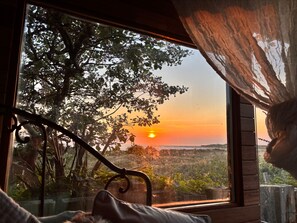 A room with a large window overlooking a landscape with a sunset view. - Coastal Cabin / 2 rooms / Sleeps 3 (Liverpool)