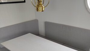 A room with a white table, grey bench seating, and a wooden floor.