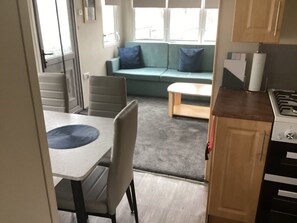 Un espacio habitable compacto con kitchenette, comedor y sofá con cojines.