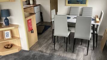 Un espacio habitable compacto con kitchenette, comedor y una pequeña zona de estar.