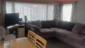 Una sala de estar con sofá, televisor y mesa.