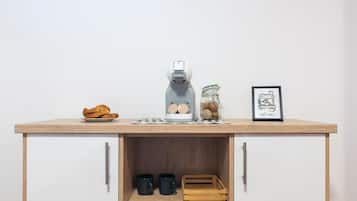 Uma cozinha compacta com cafeteira, um pote de biscoitos e uma moldura com uma fotografia no balcão.