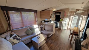 Interior moderno de una autocaravana con sala de estar, kitchenette y comedor.