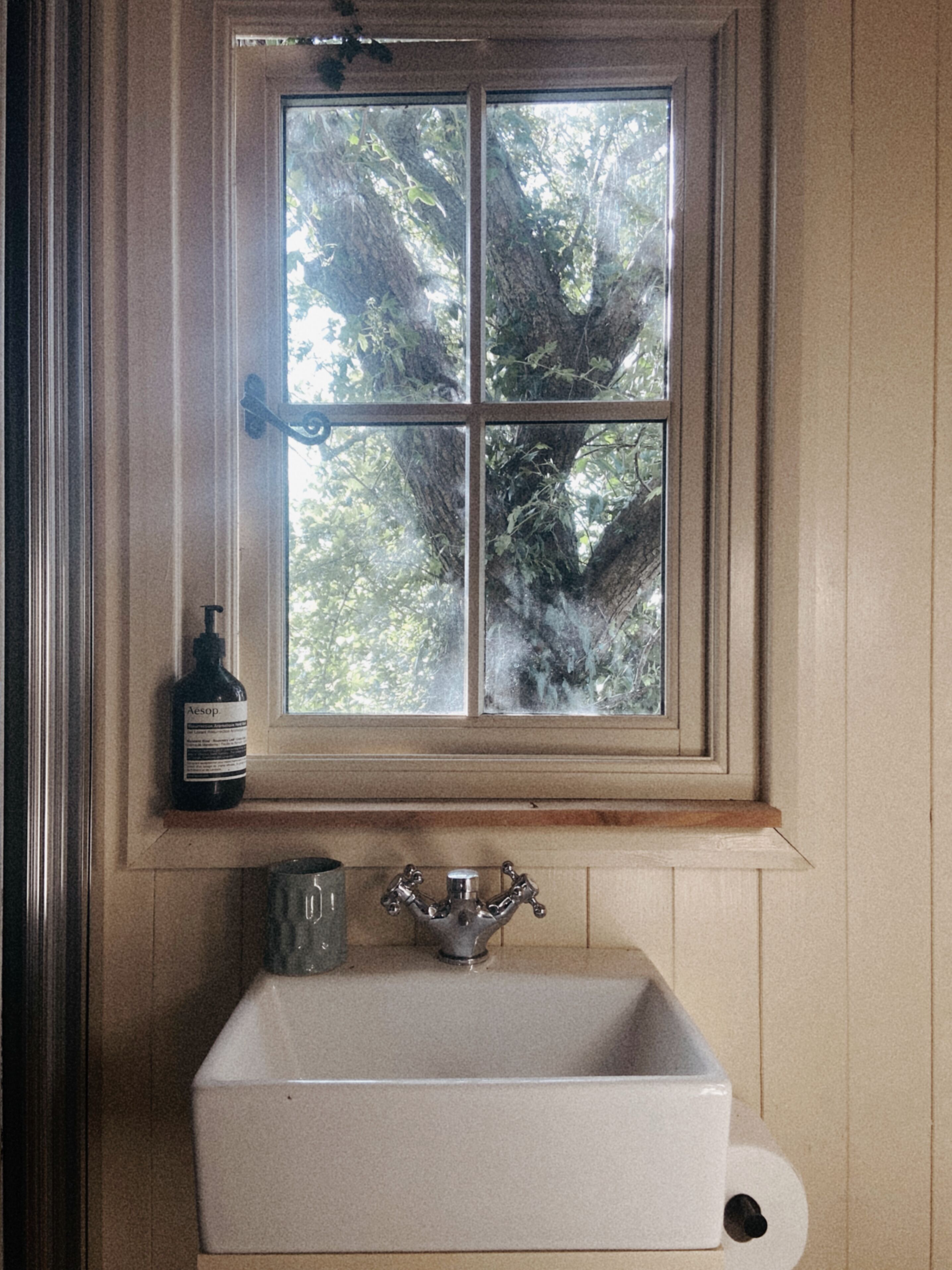 A bathroom with a window, a sink, and a bottle.